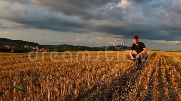 捷克共和国日落时分坐在割草场上玩玉米的年轻人天空充满戏剧性视频的预览图