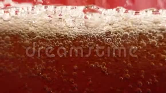 红色背景上的气泡闪闪发光在一杯冷可乐里的气泡无缝地上升视频的预览图