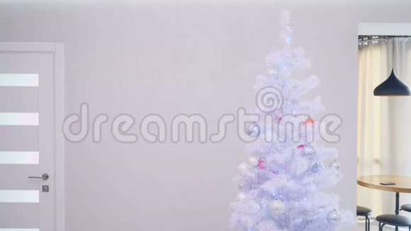 父亲和女儿坐在他的脖子上来到银色的人造圣诞树前女儿把天使的装饰品放在最上面视频的预览图