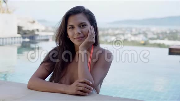 放松的年轻女子在度假胜地的游泳池里休息视频的预览图