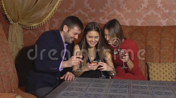 两个可爱的女人和一个男人坐在餐馆里用电话视频的预览图