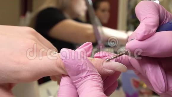 手法手术特写穿着粉色医用手套的女孩美甲师和她手中的一个特殊装置指甲护理美容视频的预览图
