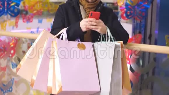 快乐购物狂的画像手里拿着纸袋用智能手机视频的预览图