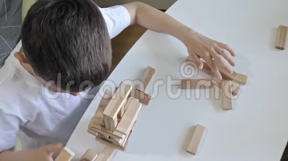 一个十几岁的白种人男孩用木块制作塔孩子们玩游戏练习身体和智力视频的预览图