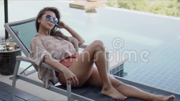 在游泳池旁的躺椅上享受度假时光的女人视频的预览图