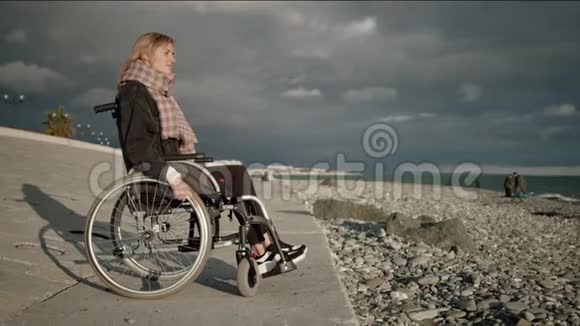 海边坐轮椅的孤残妇女视频的预览图