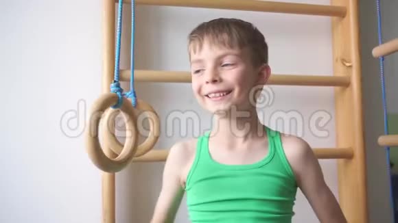男孩站在儿童健身房的体操戒指附近视频的预览图