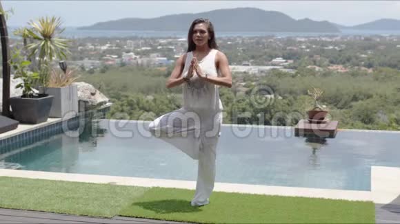 平静的女人练习瑜伽池畔对抗美丽的海岸景观视频的预览图