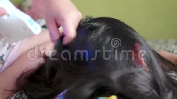 一家亚洲家庭母亲给女儿头发上的虱子视频的预览图