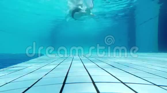 当一个人在游泳池里游泳时从水下射击一个人游离水面上的摄像机视频的预览图