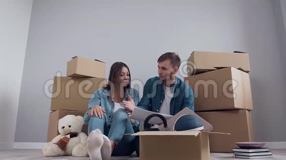 年轻的兴高采烈的快乐男女穿着时髦的衣服坐在拼花地板上讨论新的视频的预览图