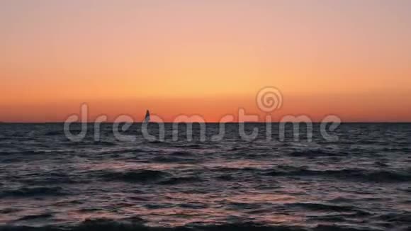 橙色黄昏小帆船剪影日落时在海上航行的小船美丽平静的大海与日落帆船视频的预览图