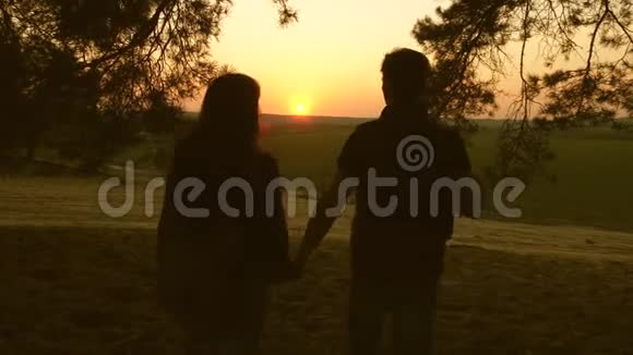 一个女人和一个男人旅行在森林里散步拥抱和欣赏日落时的风景情侣旅行者带背包旅行视频的预览图