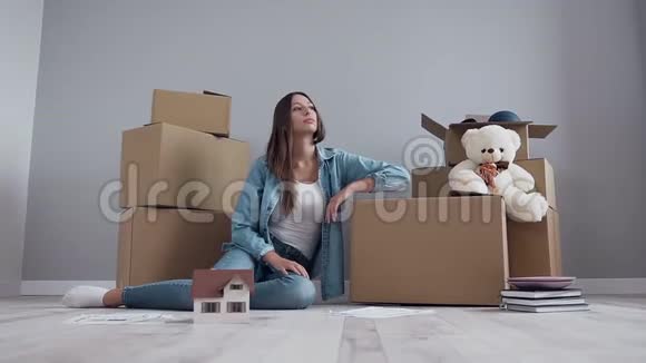 一个30岁的女孩长着一头长发穿着时尚的衣服在搬迁到盒子里后休息视频的预览图