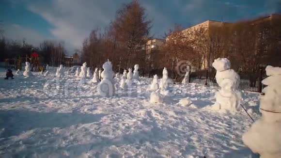 快乐的孩子在阳光明媚的冬日堆雪人视频的预览图