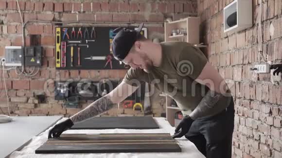 在车库里站在桌子旁的有胡子的手艺人人在车间工作有工具的木板视频的预览图