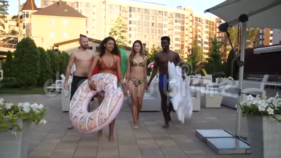 一群不同的朋友步行到酒店的游泳池视频的预览图