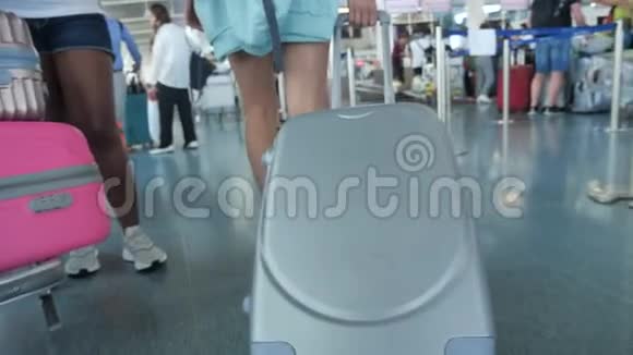 女人踩着轮子滚动手提箱女人带着她的手提箱沿着机场走旅行概念慢动作视频的预览图