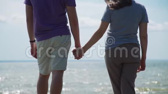 年轻夫妇手牵着手靠近大海视频的预览图