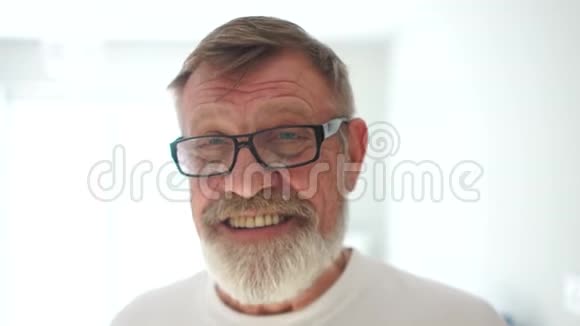 一位年长的快乐养老金领取者的肖像戴着灰色胡须和白色t恤的眼镜快乐退休视频的预览图