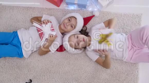 儿童躺在白色地毯上摇晃敲敲听圣诞节里面的东西的俯视视频视频的预览图