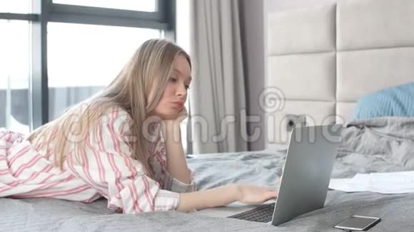 清晨躺在舒适的床上年轻女子在笔记本电脑上查看电子邮件视频的预览图