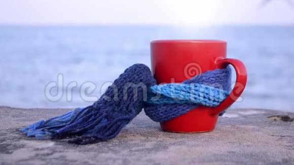 带热咖啡茶和蒸汽的红杯系着蓝色针织围巾视频的预览图