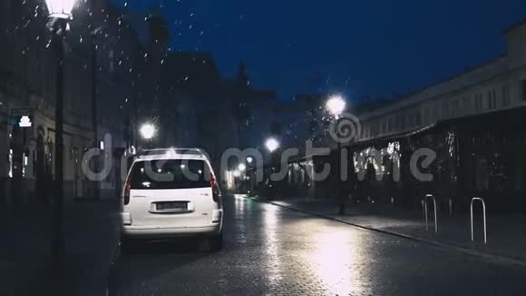 夜幕下飘落的雪花落在旧市中心空荡荡的街道上停在白色的车上如果铺路道路就是铺好的视频的预览图