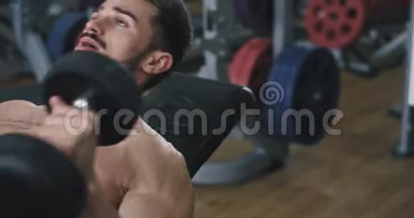 在健身房里做杠铃式长凳按压运动的肌肉发达的年轻人肖像计划视频的预览图