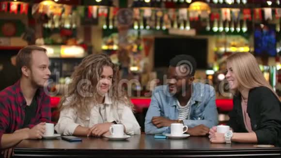 一家由学生朋友组成的跨国公司喝咖啡在餐馆里交谈四个朋友谈笑风生视频的预览图