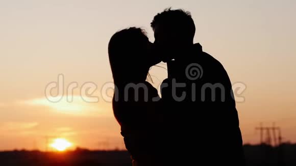 日落时分第一对可爱的年轻夫妇温柔亲吻的剪影视频的预览图
