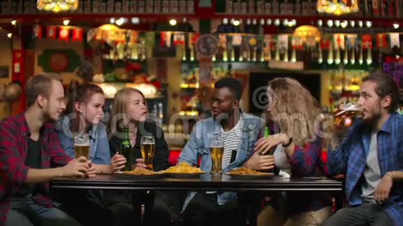 多民族青年男女在酒吧喝啤酒并就大学进行有趣的讨论视频的预览图