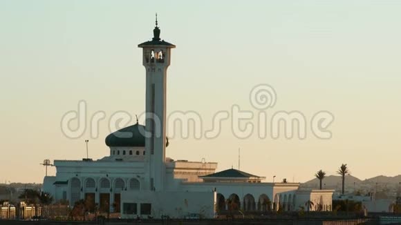 日落时有绿色圆顶的老白清真寺背景中的棕榈树和山脉视频的预览图