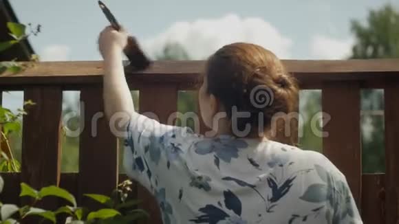 红头发的女孩用刷子画一个木栅栏视频的预览图