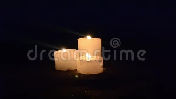 三支黄色的小蜡烛靠近海边的沙滩海浪视频的预览图