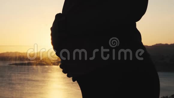 美丽的孕妇在夕阳下抚摸她的腹部女人摸她的肚子快乐的准妈妈视频的预览图