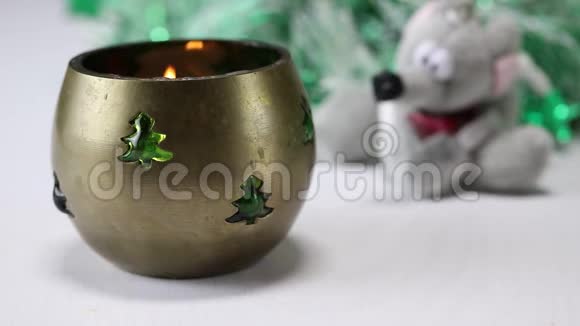 火在一个金属装饰的圣诞烛台上燃烧背景是一棵人造圣诞树和一个软玩具视频的预览图