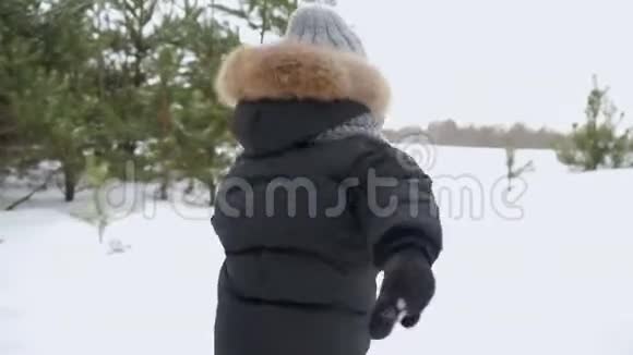 穿着暖和的衣服的小男孩跑到他的父母身边在冬天的森林里拥抱他们视频的预览图