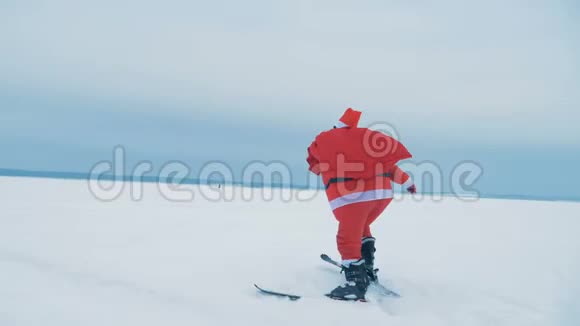 圣诞老人正拿着一袋礼物在雪地上滑雪视频的预览图