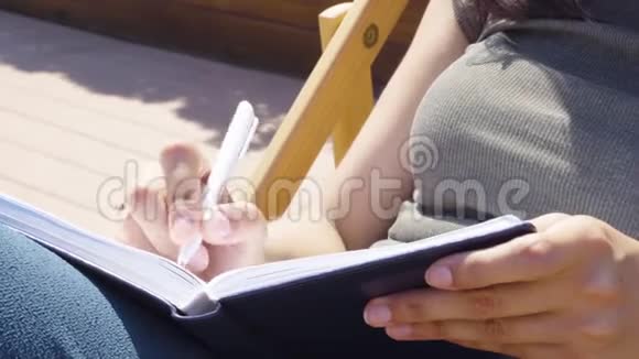 特写女性手在笔记本上做笔记视频的预览图