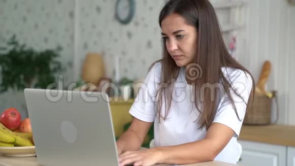 疲惫的女孩在家里的笔记本电脑上工作头痛得厉害动作迟缓视频的预览图