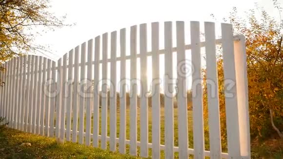 美丽的白色篱笆和绿色的草坪明亮的阳光相机在运动视频的预览图