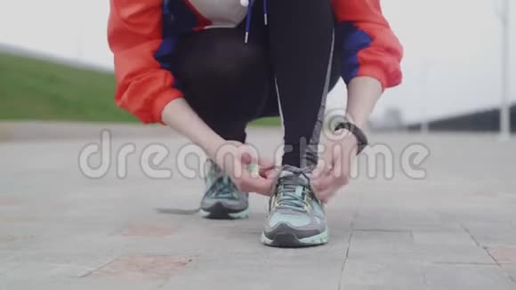 年轻的健身女子在公园里系运动鞋跑鞋带视频的预览图