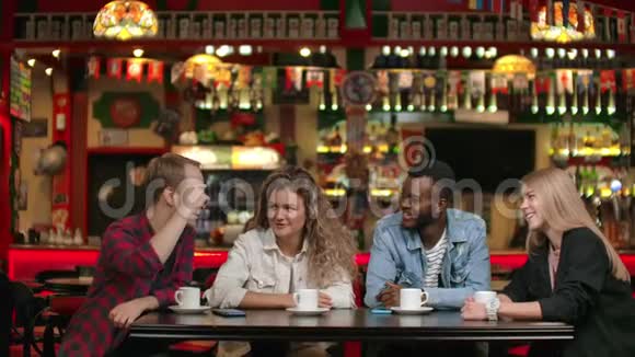 在一家餐馆里一群快乐的多民族朋友在喝咖啡谈论和谈论关于视频的预览图