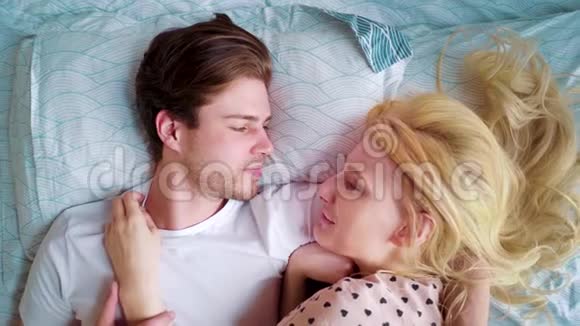 顶景缩小了年轻夫妇在床上的早晨互相微笑视频的预览图