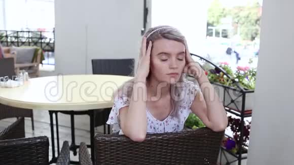 穿着夏装的少女坐在咖啡馆的柳条椅上摆姿势视频的预览图