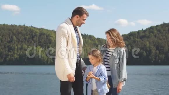 一个年轻家庭在美丽湖泊背景上的肖像视频的预览图