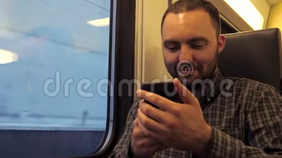 英俊的男人坐在地铁里用他的智能手机上网视频的预览图