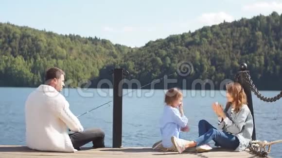 幸福的家庭和女儿花时间在美丽的湖边钓鱼视频的预览图