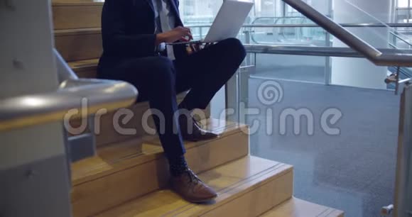 在办公室楼梯上使用笔记本电脑的商人视频的预览图